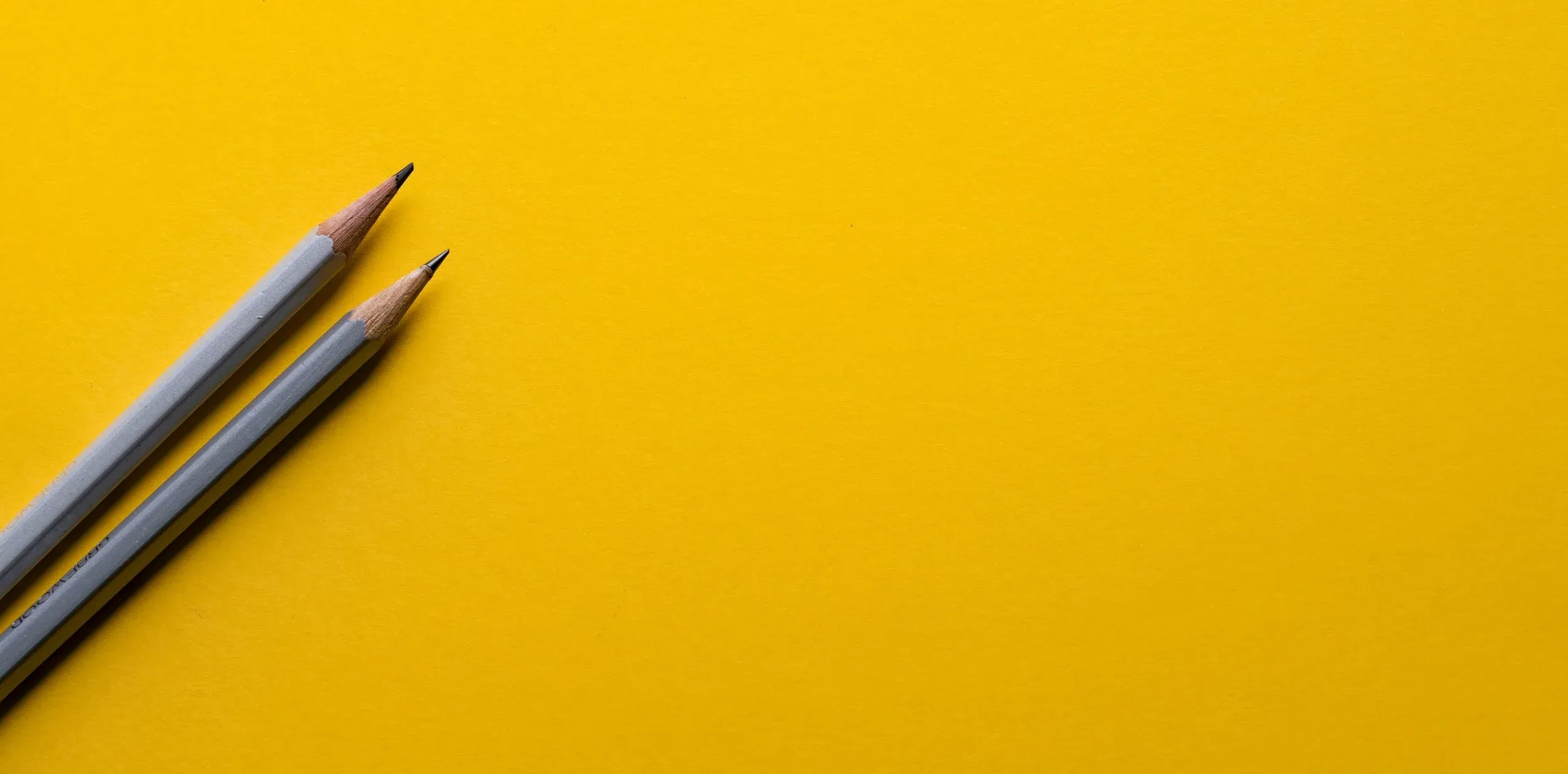 Pencils over yellow background for coding qualitative data.